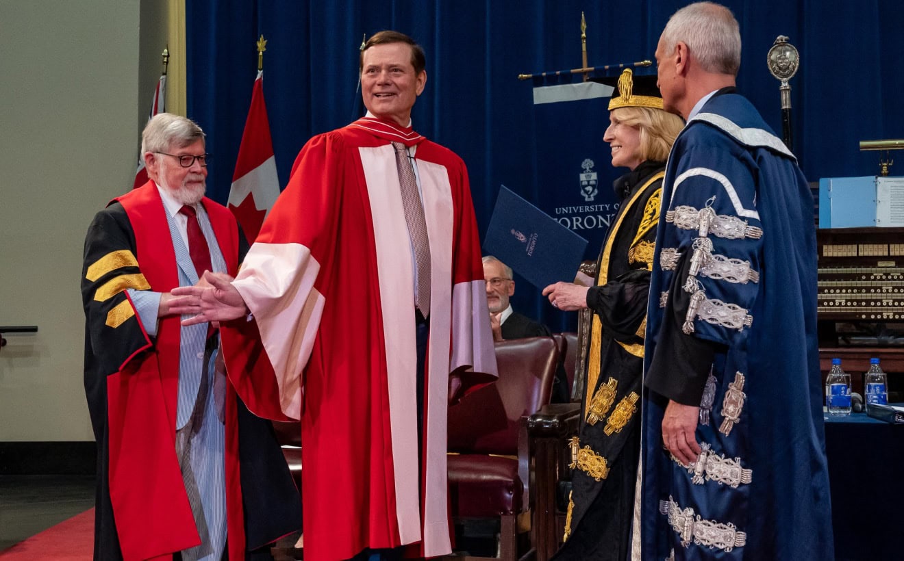 Blake Goldring receiving his degree wearing a red gown